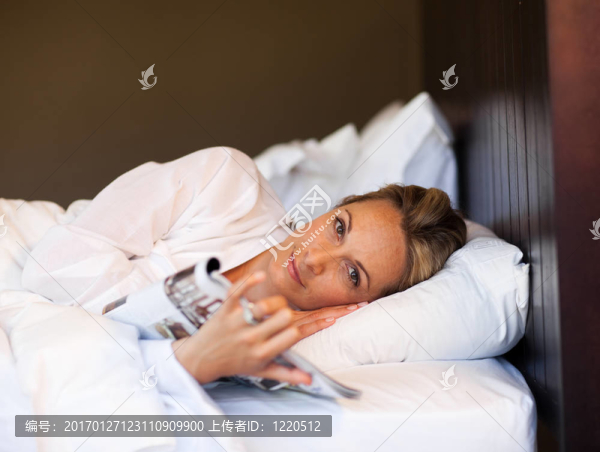年輕的女人在床上看雜志