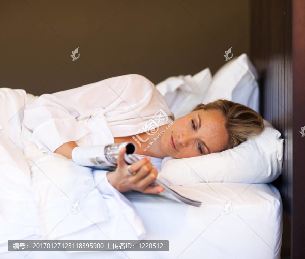 年輕的女人在床上看雜志