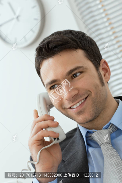 年輕的商人在固定電話在辦公室；微笑。
