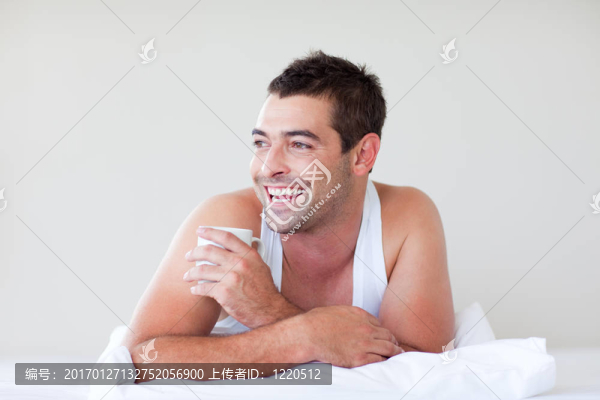 男子在床上喝一杯咖啡
