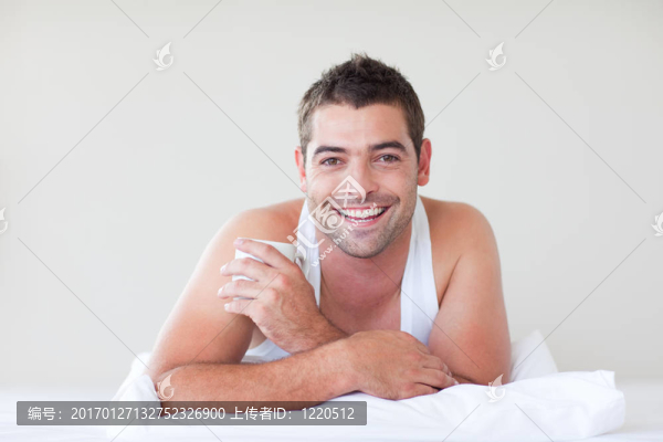 男子在床上喝一杯咖啡