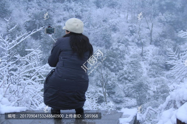 雪景中拿自拍桿自拍的女人