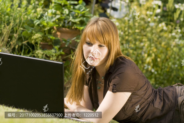 在花園里的筆記本電腦上的年輕女子