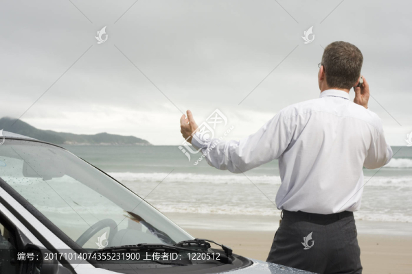 經(jīng)理在海灘旁的汽車旁打電話。