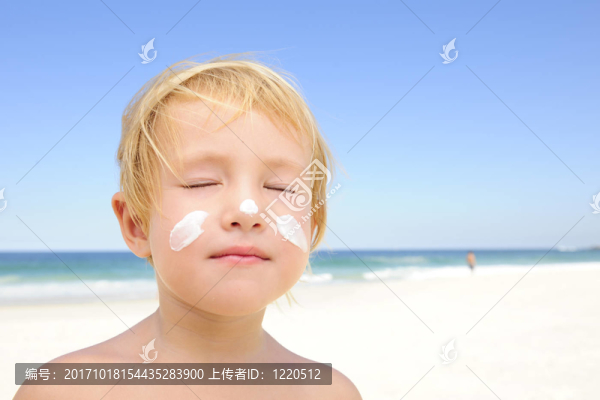 海灘上臉上涂著防曬油的孩子