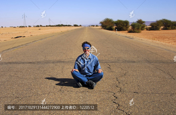 年輕的女人盤腿坐在中間的landstr瀝青絲帶
