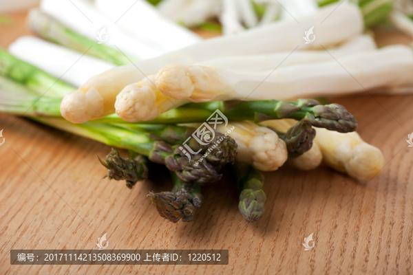 在一張橡木桌上的未加工的白色和綠色蘆筍