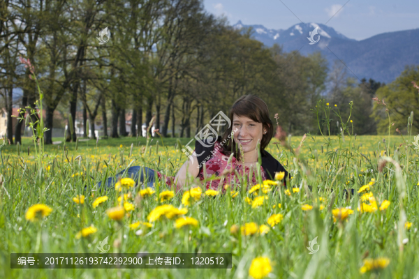 年輕女子躺在草和蒲公英