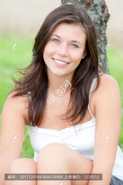 年輕漂亮的女孩坐在一棵樹下