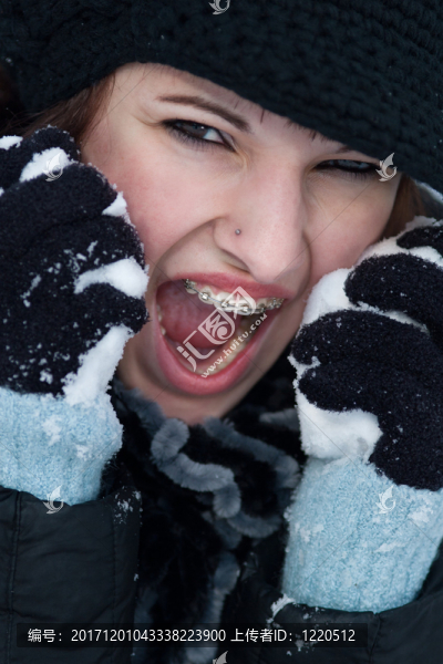 年輕尖叫的女人帶著大括號的帽子和圍巾堅(jiān)持雪上的雪