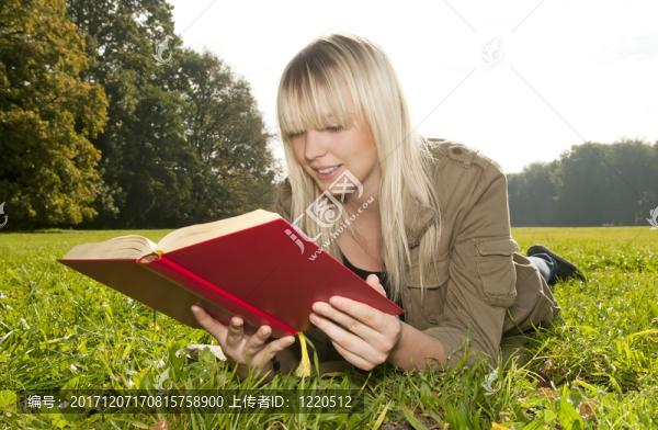 年輕女子在一片草地上看書