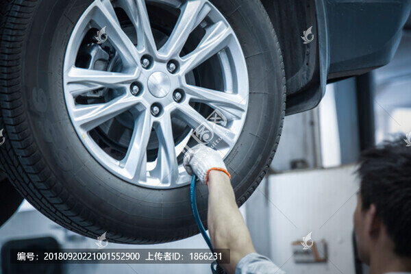 4S店內(nèi)汽車維修工檢查胎壓