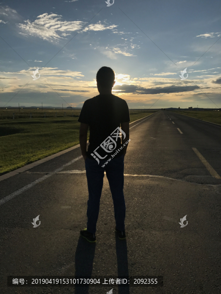 落日下草原公路上的人物剪影豎幅