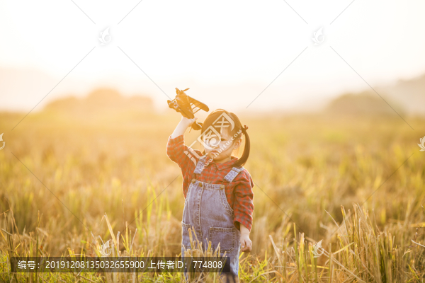 小女孩拿著飛機(jī)玩具在田野玩耍