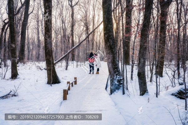 一對情侶在雪地中的木棧道上行走
