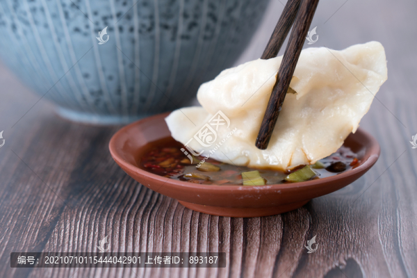 碗旁邊筷子夾著正要蘸蘸水的餃子