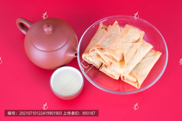 紅背景上一盤炸春卷和茶壺茶碗