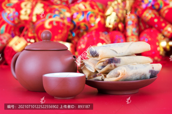 喜慶背景前一盤炸春卷和茶壺茶碗