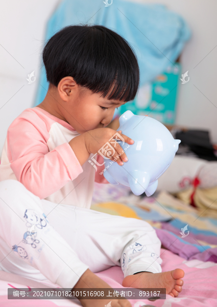 小女孩正好奇的觀察小豬存錢罐