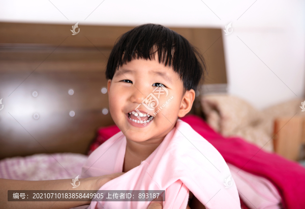 正在床上穿上衣的小女孩