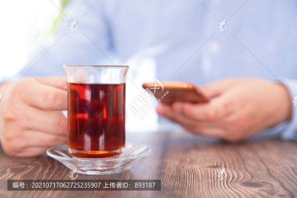 玩著手機(jī)休閑的喝茶者