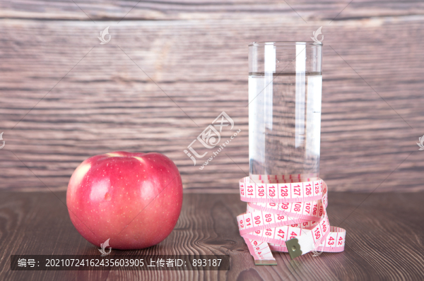 一個(gè)蘋果和被尺子纏繞的一瓶水