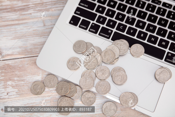 筆記本電腦鍵盤上散落的美元硬幣