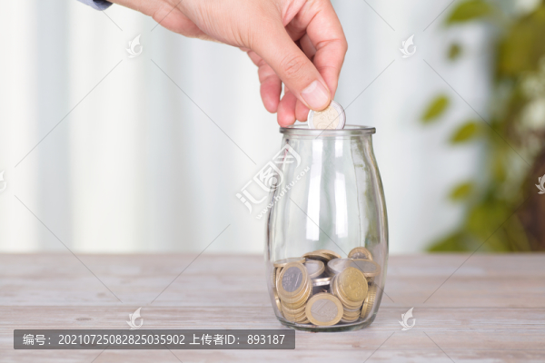 手拿歐元硬幣準(zhǔn)備放進(jìn)玻璃瓶里