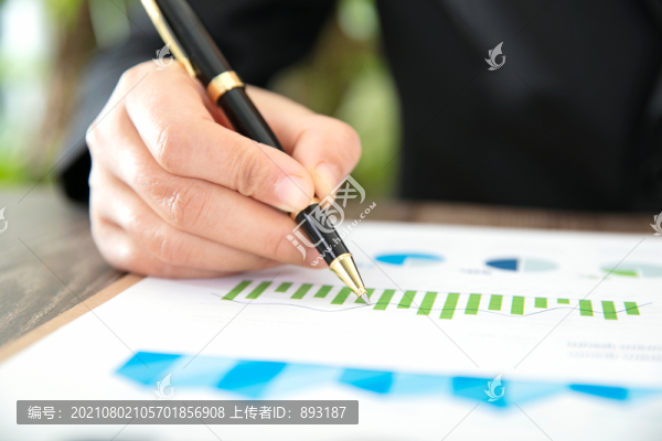 特寫手握一支筆在查看金融走勢(shì)圖