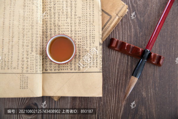 毛筆及放在書上的一碗茶