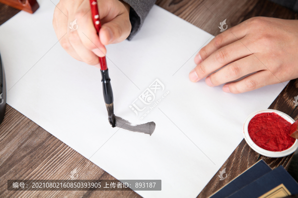 手拿毛筆在紙上練習(xí)毛筆字