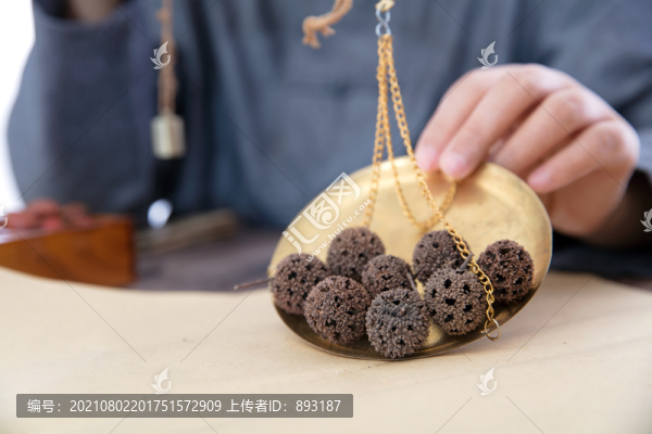 把秤盤里的中藥楓球子倒在草紙上
