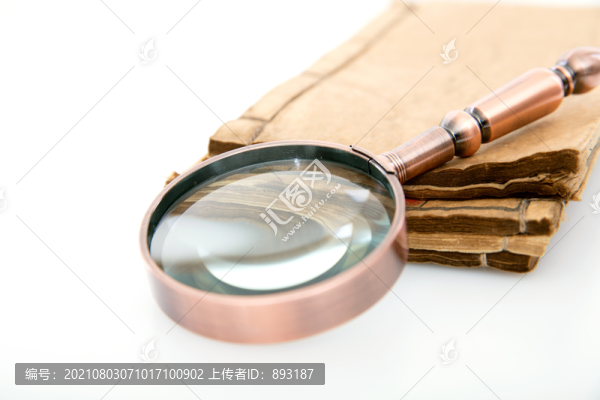 白背景上翻開的舊書和放大鏡