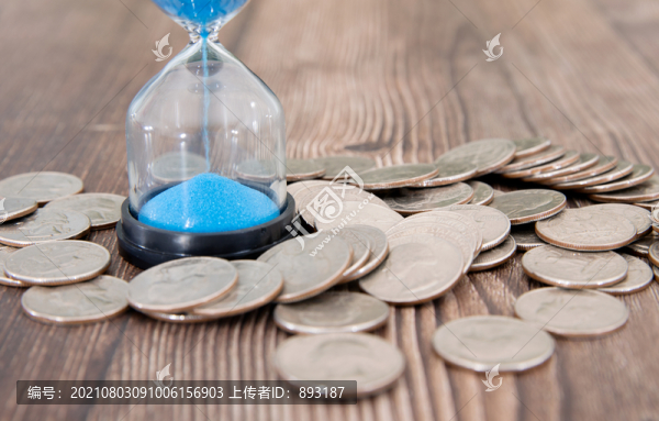 桌子上一堆美元硬幣和沙漏
