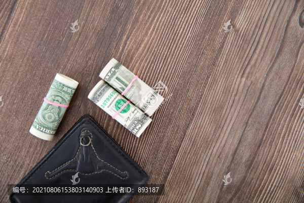 桌子上的錢包和卷筒狀的美元鈔票