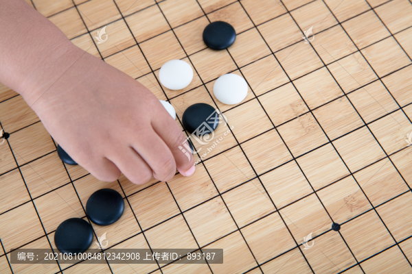 手拿著棋子在圍棋棋盤上下棋