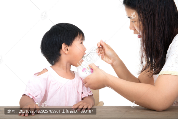 年輕媽媽正給可愛(ài)的女兒喂飯