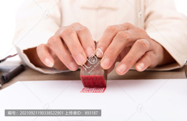 中國(guó)人手拿印章在白紙上加蓋
