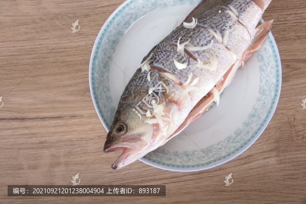 盤子里放著一條正在腌制的鱸魚