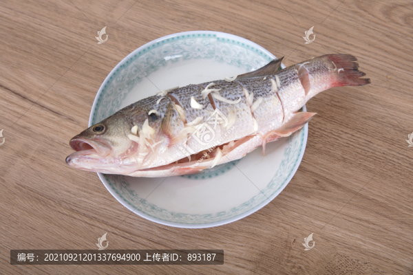 盤子里放著一條正在腌制的鱸魚