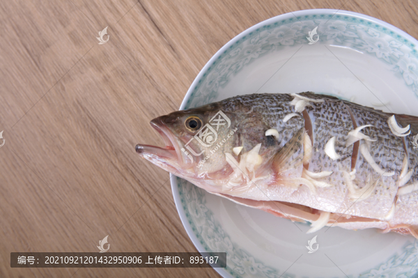 盤子里放著一條正在腌制的鱸魚