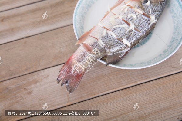 盤(pán)子里放著一條正在腌制的鱸魚(yú)