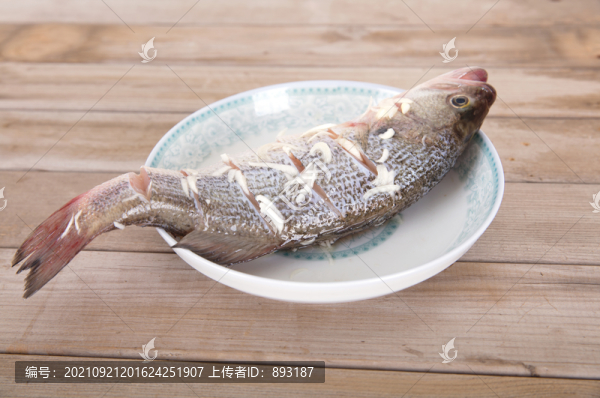 盤子里放著一條正在腌制的鱸魚