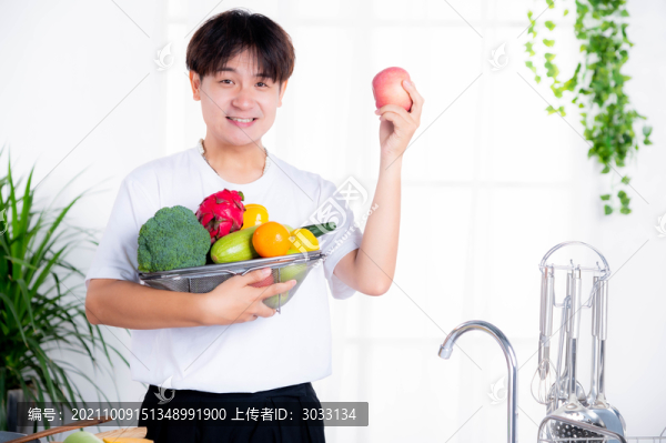 男人在廚房抱蔬菜水果