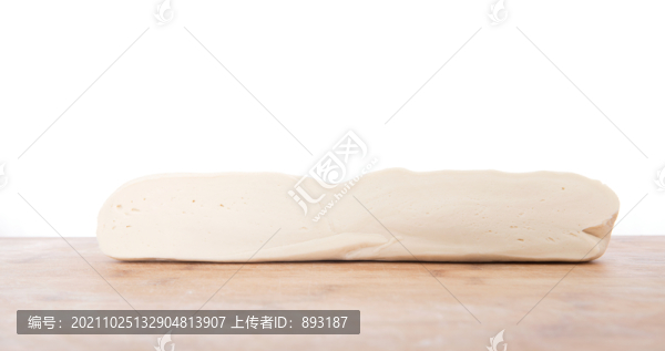 白背景前的砧板上一條白面團(tuán)