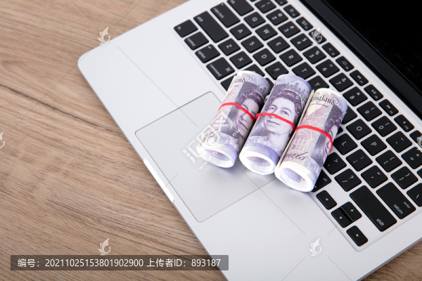 筆記本電腦鍵盤上三卷英鎊鈔票