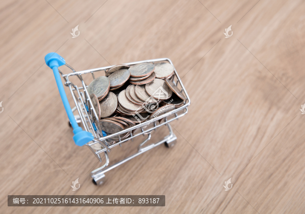 桌子上一輛滿載美元硬幣的小購(gòu)物