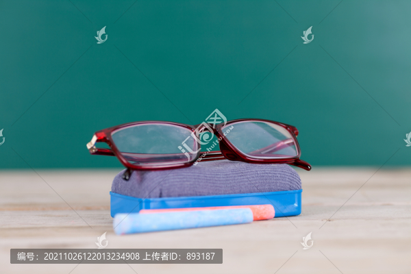 黑板背景前的黑板擦和眼鏡