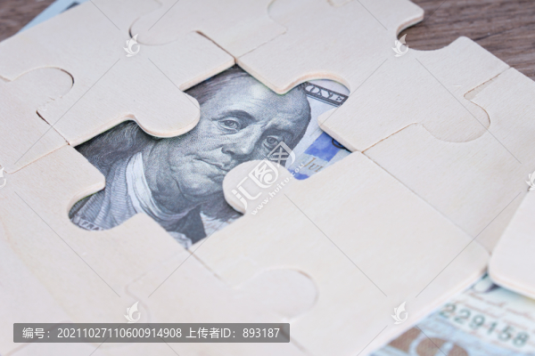 桌子上拼圖游戲露出的美元鈔票