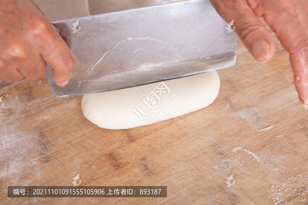 手拿菜刀把砧板上的面團(tuán)切開